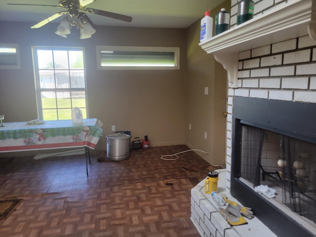 living room featuring a fireplace, a ceiling fan, and baseboards