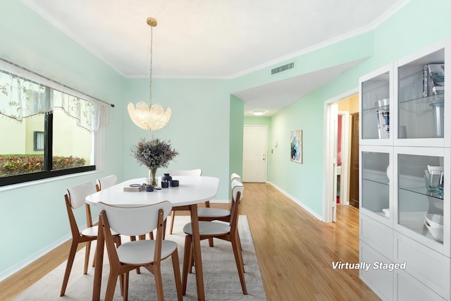 6941 SE Constitution Blvd Unit 101, Hobe Sound, FL 33455 - dining area with light wood-style flooring, a chandelier, ornamental molding, and baseboards