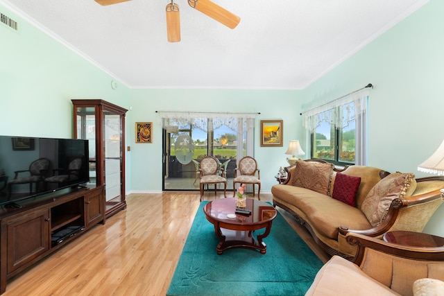 living area featuring light wood-type flooring, visible vents, a ceiling fan, crown molding, and baseboards