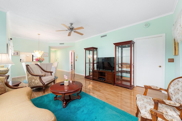 living room featuring visible vents, light wood-style flooring, ceiling fan with notable chandelier, and crown molding