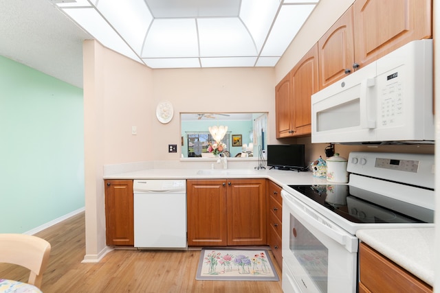 kitchen with white appliances, light countertops, and light wood finished floors