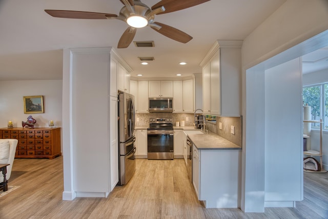 kitchen with tasteful backsplash, visible vents, stainless steel appliances, a ceiling fan, and a sink