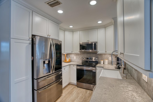 kitchen featuring visible vents, light countertops, decorative backsplash, appliances with stainless steel finishes, and light wood-style floors