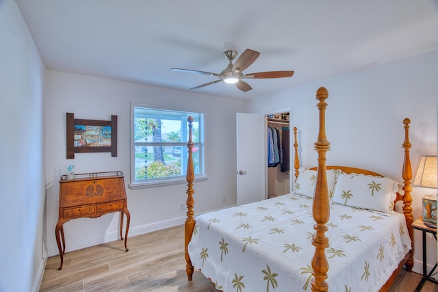 bedroom featuring wood finished floors, a closet, baseboards, ceiling fan, and a spacious closet