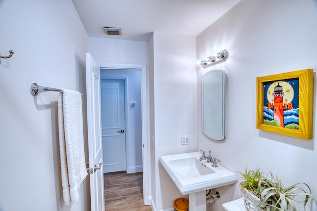 bathroom featuring visible vents, a sink, and wood finished floors