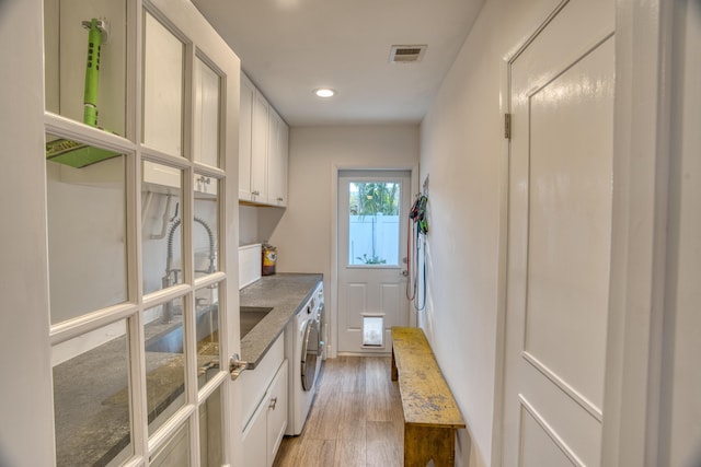 washroom featuring visible vents, light wood-style flooring, recessed lighting, cabinet space, and washer and clothes dryer