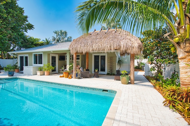 rear view of property featuring a patio area, stucco siding, a fenced in pool, and fence