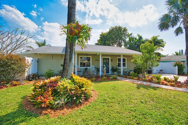 ranch-style house with a shingled roof, fence, a porch, a front yard, and stucco siding