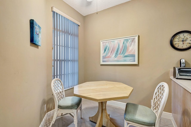 tiled dining room featuring a textured ceiling and baseboards