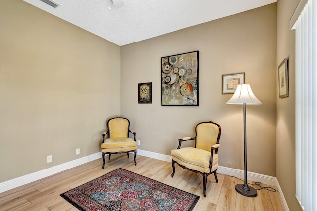 sitting room featuring visible vents, ceiling fan, baseboards, and light wood-style floors