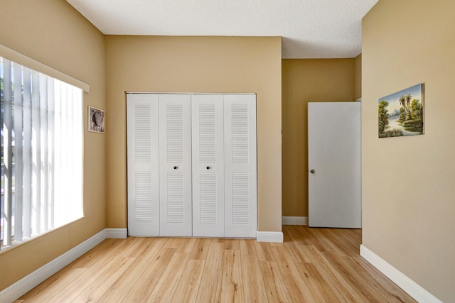 unfurnished bedroom with multiple windows, light wood-style flooring, and baseboards