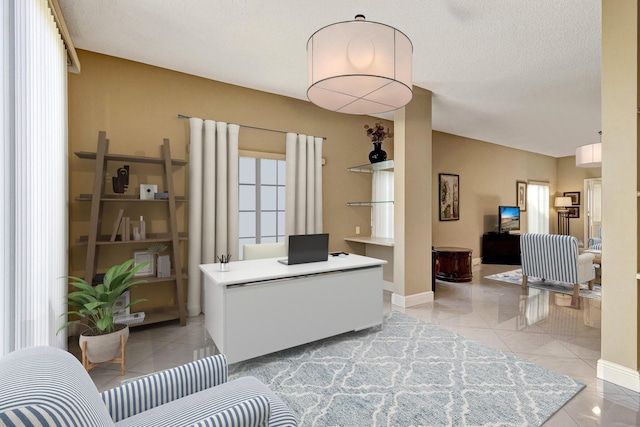 office area with light tile patterned flooring, a textured ceiling, and baseboards