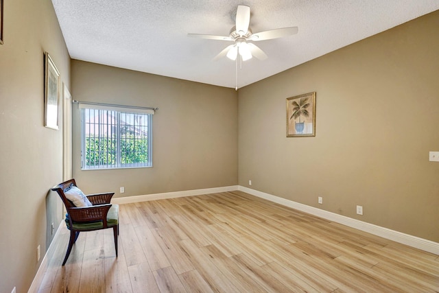 unfurnished room with baseboards, a textured ceiling, light wood-style flooring, and a ceiling fan