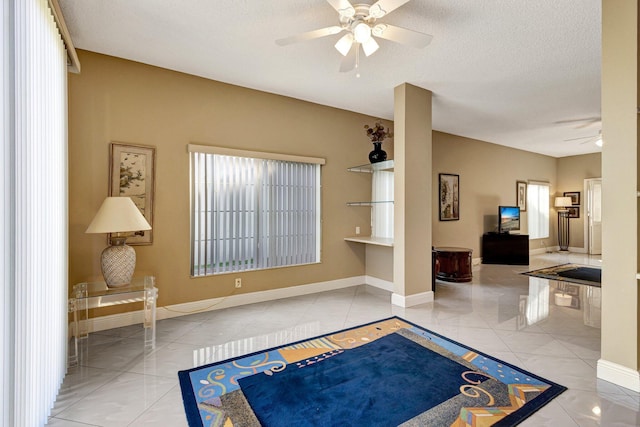 tiled foyer entrance with baseboards, a textured ceiling, a healthy amount of sunlight, and ceiling fan