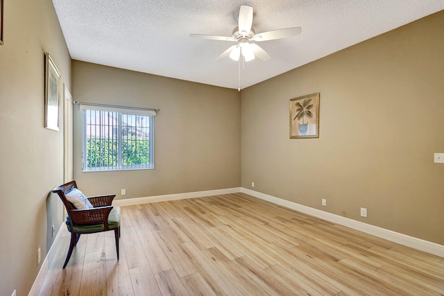 unfurnished room featuring light wood finished floors, a textured ceiling, baseboards, and ceiling fan