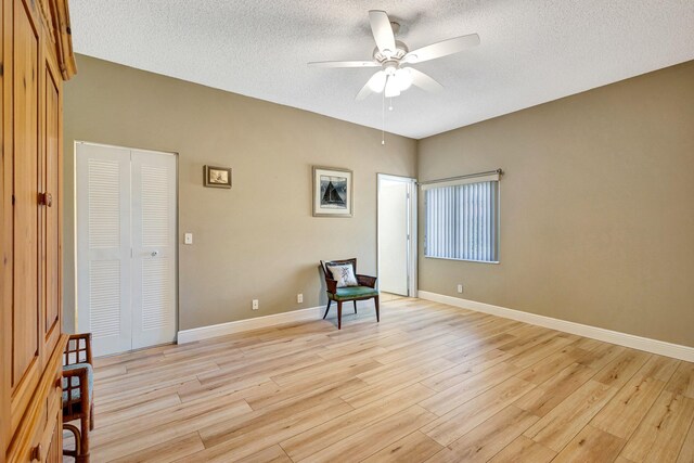 unfurnished room with light wood-type flooring, baseboards, a textured ceiling, and a ceiling fan