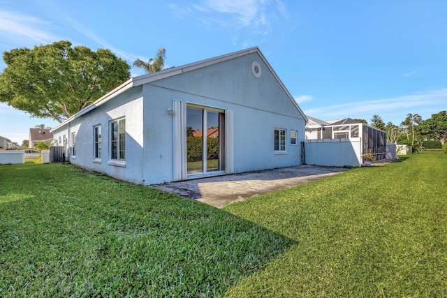 back of property with stucco siding, a patio, and a lawn