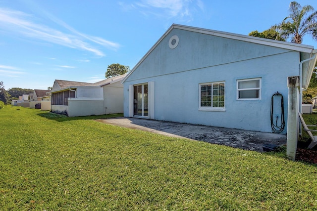 rear view of house featuring a yard, a patio area, and stucco siding