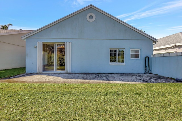 back of house featuring stucco siding and a lawn