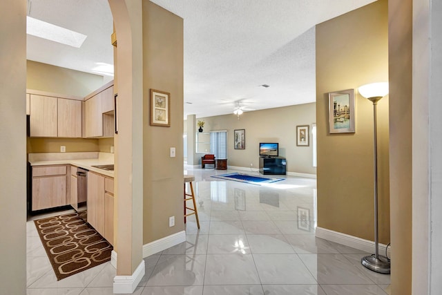 corridor with arched walkways, a textured ceiling, and baseboards