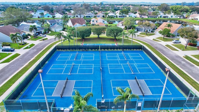 view of tennis court featuring a residential view and fence