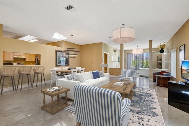 living room with light tile patterned flooring, visible vents, and baseboards