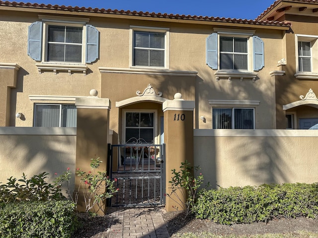 view of front facade featuring a gate, central AC unit, a fenced front yard, and stucco siding