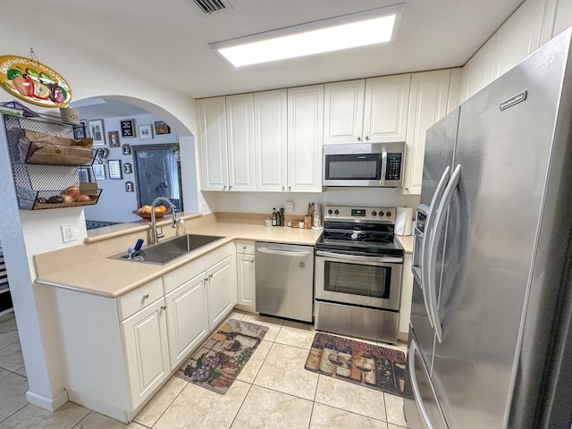 kitchen with white cabinetry, stainless steel appliances, light countertops, and a sink