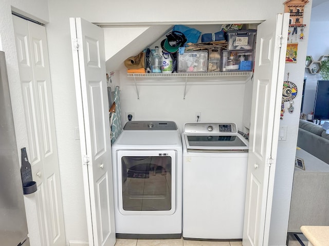 laundry room featuring light tile patterned flooring, laundry area, and washing machine and dryer