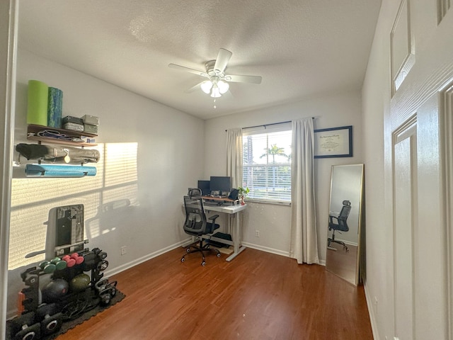 office space featuring a ceiling fan, wood finished floors, baseboards, and a textured ceiling