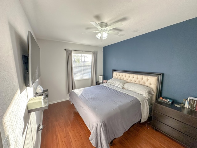 bedroom featuring baseboards, wood finished floors, and a ceiling fan