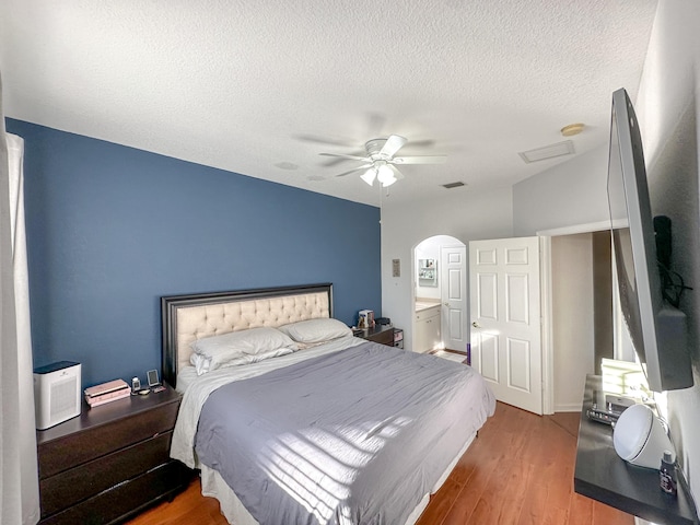 bedroom with a ceiling fan, visible vents, wood finished floors, arched walkways, and a textured ceiling