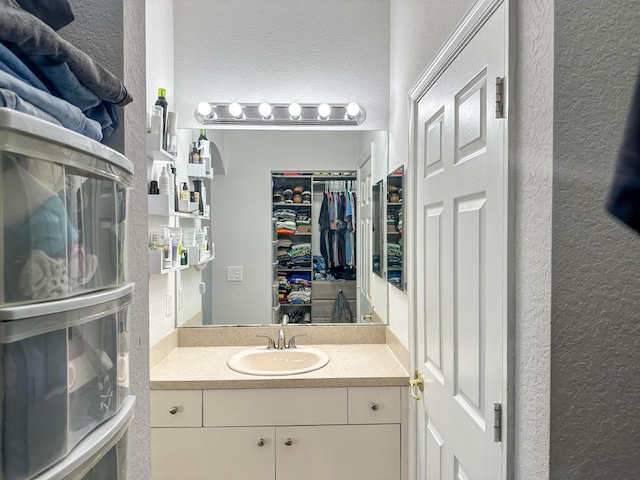 bathroom featuring vanity, a spacious closet, and a textured wall