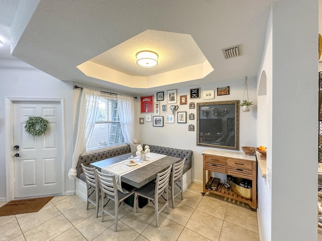 dining space with light tile patterned floors, visible vents, a tray ceiling, a textured ceiling, and breakfast area