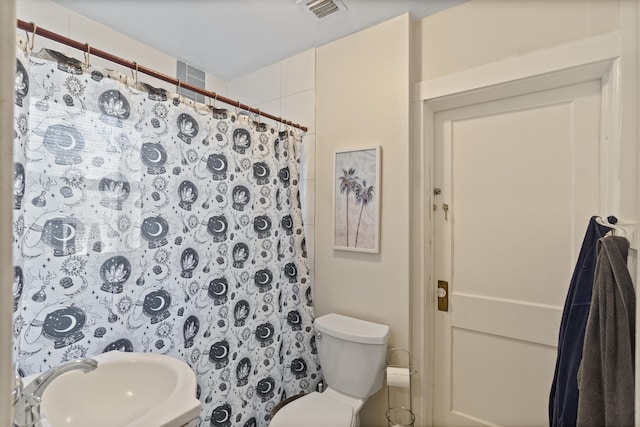 bathroom featuring visible vents, toilet, a shower with shower curtain, and a sink