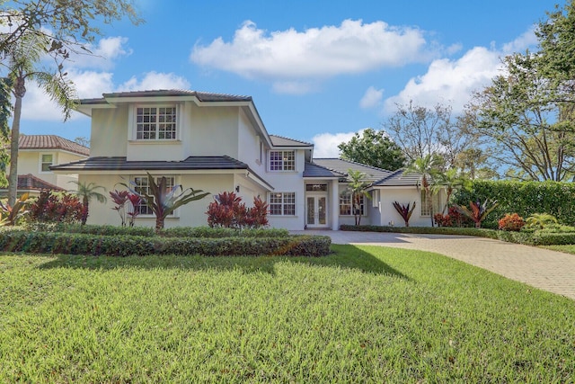 view of front facade featuring stucco siding, decorative driveway, and a front lawn