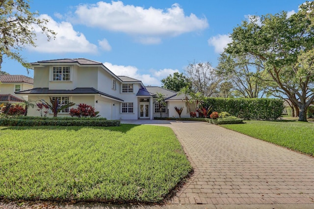 view of front of house with a front yard, decorative driveway, and stucco siding