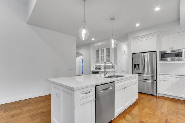 138 Victorian Ln, Jupiter, FL 33458 - kitchen with a kitchen island with sink, arched walkways, a sink, light countertops, and stainless steel appliances