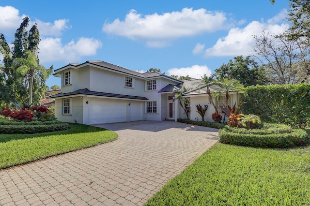 view of front of home featuring stucco siding, an attached garage, decorative driveway, and a front yard