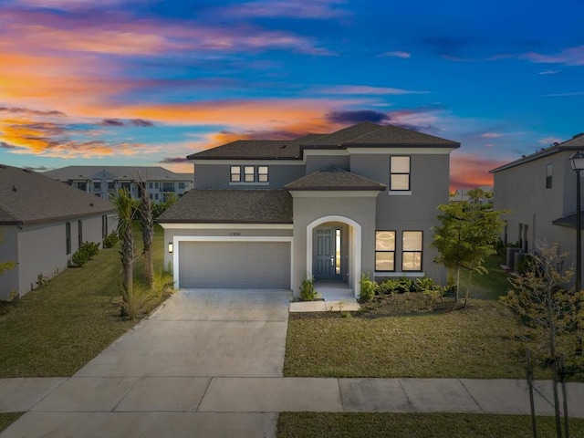 view of front facade featuring stucco siding, driveway, a front yard, and a garage