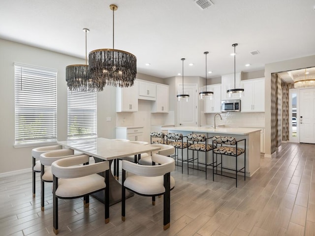 dining space with light wood finished floors, visible vents, baseboards, recessed lighting, and a notable chandelier