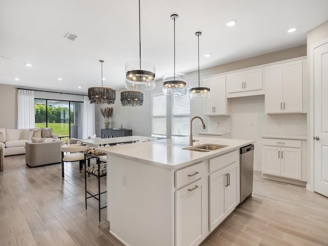 kitchen featuring visible vents, a sink, open floor plan, light wood-style floors, and dishwasher