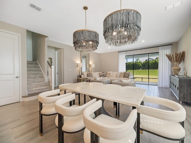 dining room featuring light wood-style floors, a notable chandelier, visible vents, and stairs