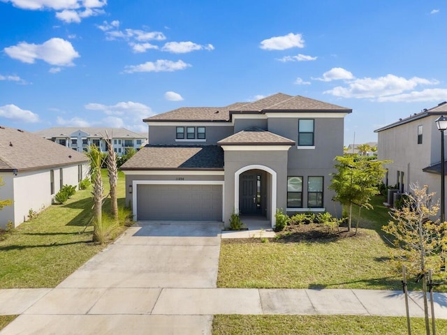 view of front of property with roof with shingles, driveway, an attached garage, stucco siding, and a front lawn