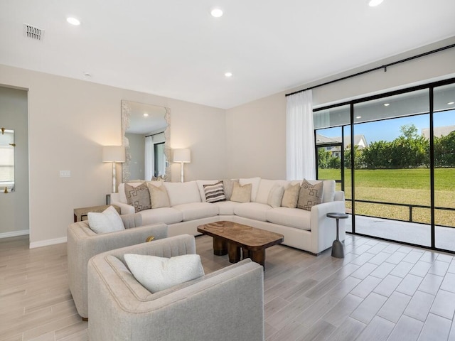 living room with light wood finished floors, visible vents, recessed lighting, and baseboards