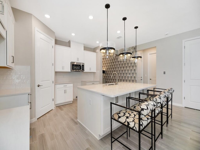 kitchen featuring wood finish floors, stainless steel microwave, and white cabinetry