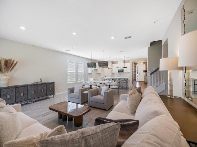 living area with visible vents, baseboards, stairway, recessed lighting, and wood finished floors