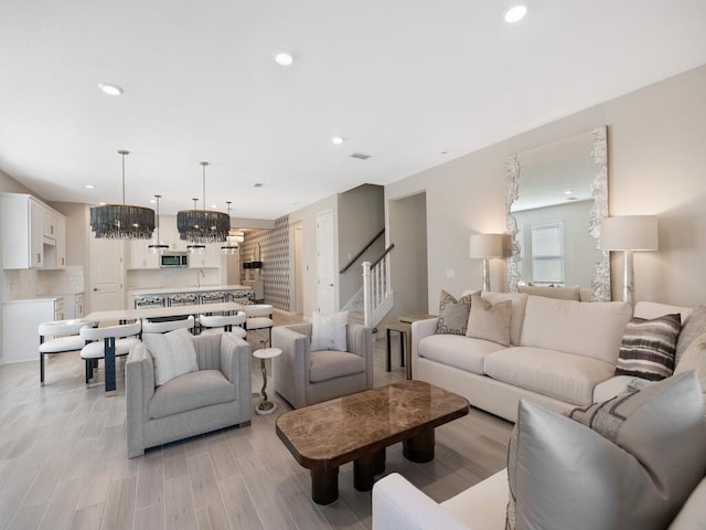 living room featuring visible vents, recessed lighting, stairway, an inviting chandelier, and light wood finished floors