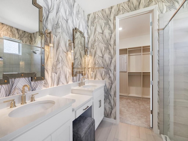 bathroom featuring a sink, double vanity, a spacious closet, and wallpapered walls