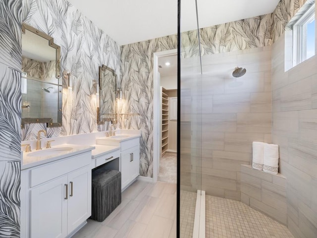 full bath featuring a walk in closet, a sink, wallpapered walls, double vanity, and walk in shower